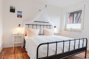 A bedroom with a bed, bedside tables, a window, and wall art.