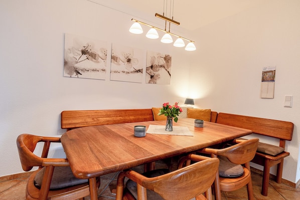 A dining area with a wooden table and chairs, a vase of flowers, and wall art.