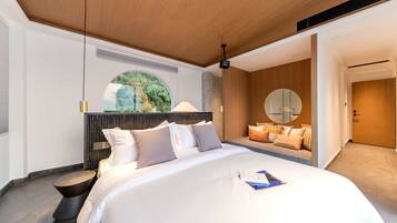 Un dormitorio moderno con una cama grande, un espejo redondo y vistas a la vegetación a través de una ventana.
