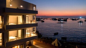 Un hotel moderno con varios balcones que dan a un puerto deportivo al atardecer.
