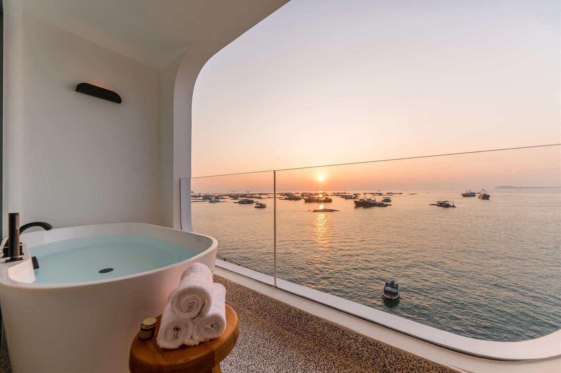 Une salle de bain avec une baignoire et une vue sur les bateaux au coucher du soleil.