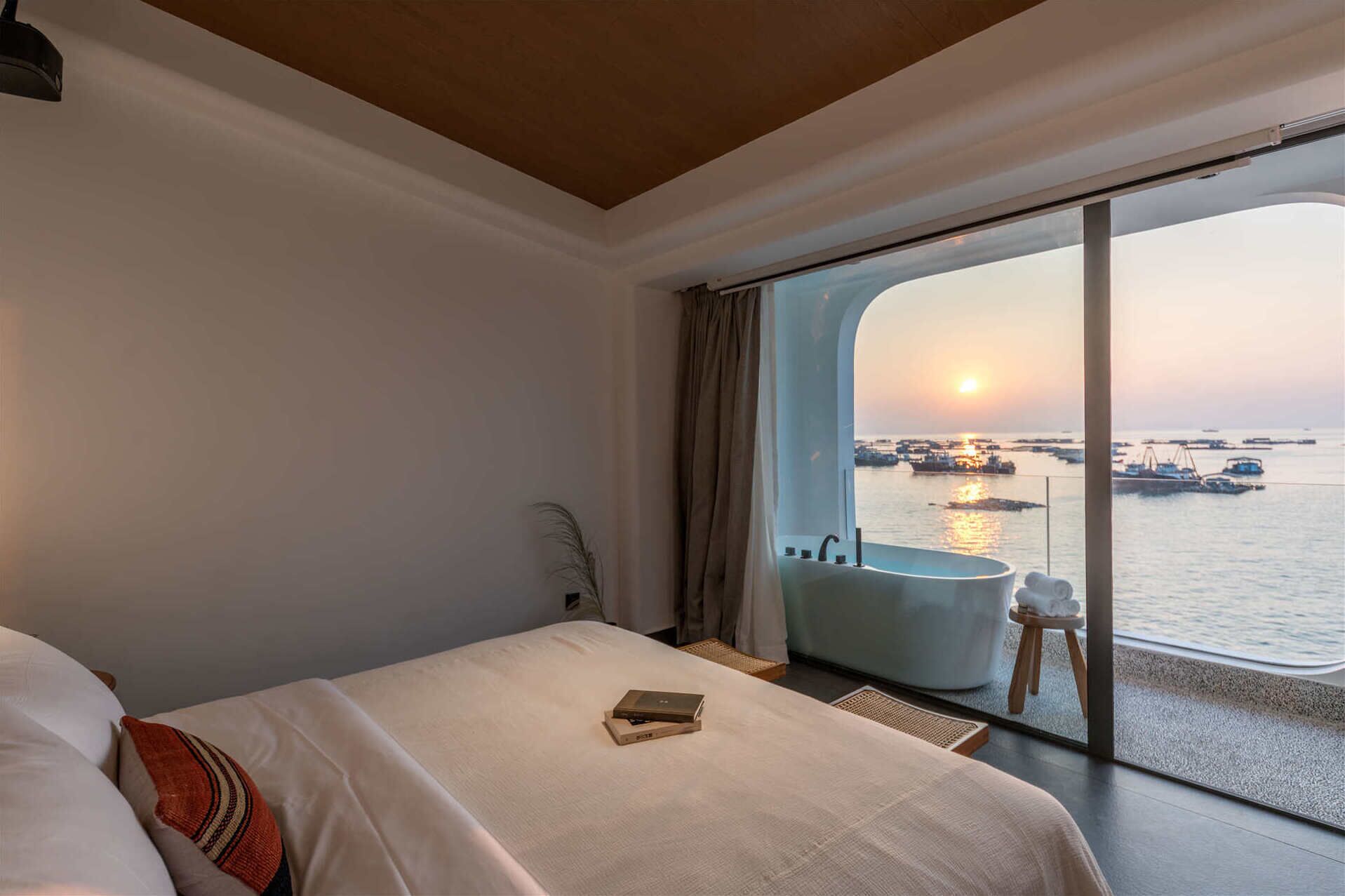 Una camera d'albergo con un letto grande, vista sul mare e una vasca da bagno.