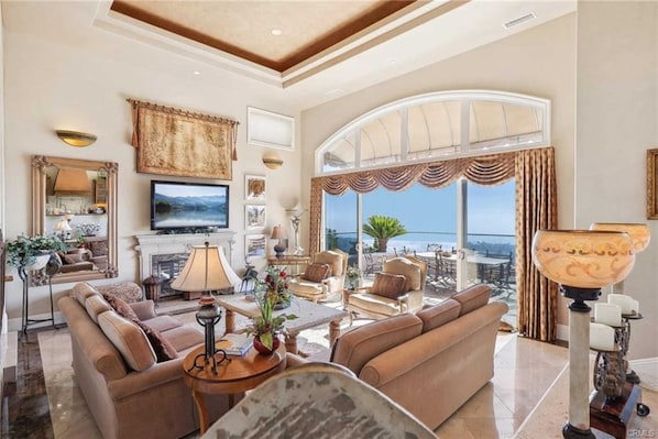 A spacious living room with a large arched window, a fireplace, and a television.