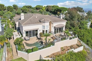 A modern two-story house with a swimming pool, large windows, and a well-maintained garden.