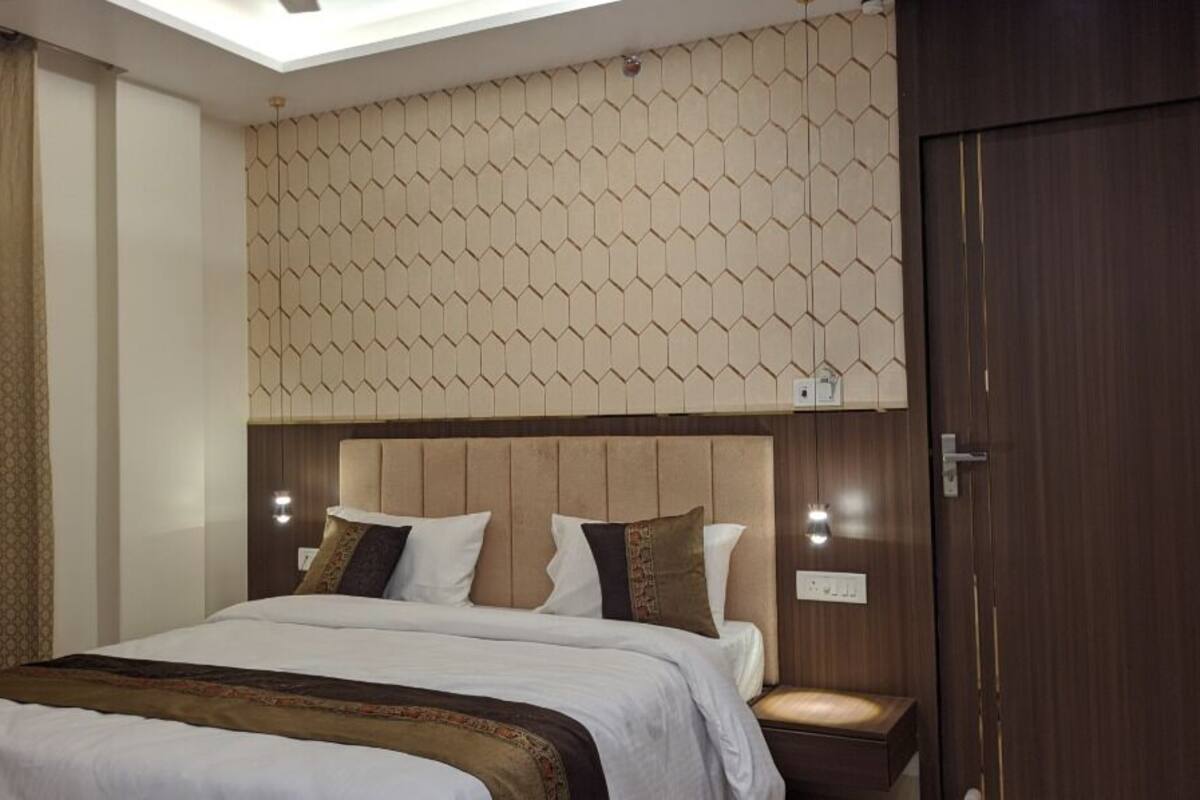 Una habitación de hotel con una cama, cabecera de diseño geométrico, mesita de noche y una puerta.