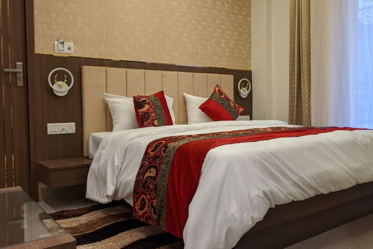 Una habitación de hotel con una cama, una mesita de noche, un reloj de pared y una ventana con cortinas.