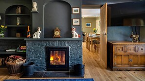 Ein gemütliches Wohnzimmer mit Kamin aus Stein, Holzmöbeln und Dekorationselementen.