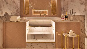 Une salle de bain luxueuse avec un lavabo en marbre, un banc intégré et un miroir doté de panneaux rétroéclairés.