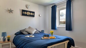 A bedroom with a bed, a bedside table with a lamp, a tray with breakfast items, and a window with curtains. - Apartment in Llanberis near Snowdonia Park (Llanberis)