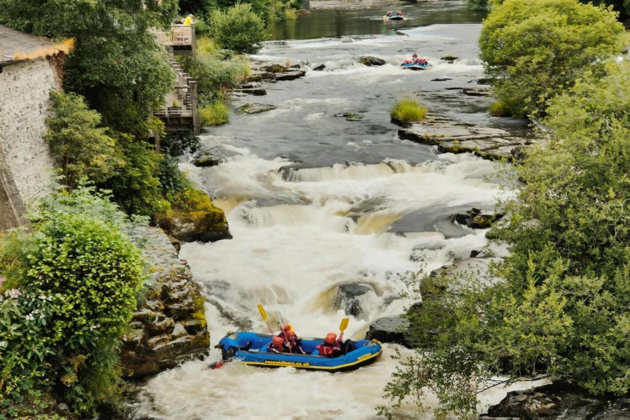 Een rivier met torenhoge golven en een blauwe raft met roeiers.