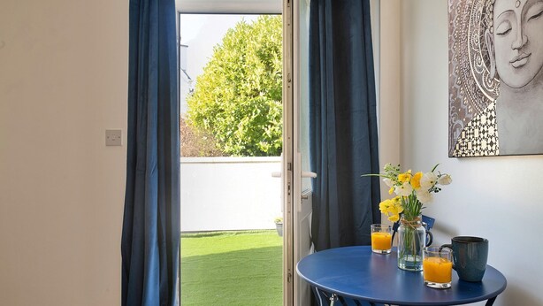 A room with a door leading to a balcony, a table with drinks and a vase of flowers, and a painting on the wall. - Apartment in Llanberis near Snowdonia Park (Llanberis)