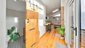 Un interior moderno con una puerta corredera de madera, una zona de cocina con taburetes y una pared de acento de piedra.