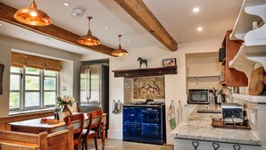 Una cocina con un banco de madera, un horno azul y luces colgantes.