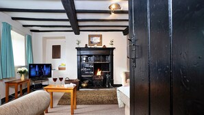 A cozy living room with a fireplace, a television, and a sofa. - Cottage in Grasmere near Lake & Scenic Trails (Grasmere)