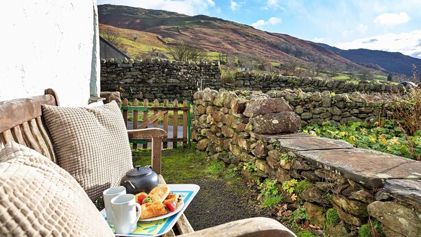 A stone wall, a wooden bench, and a table with a plate of food and cups. - Cottage in Grasmere near Lake & Scenic Trails (Grasmere)