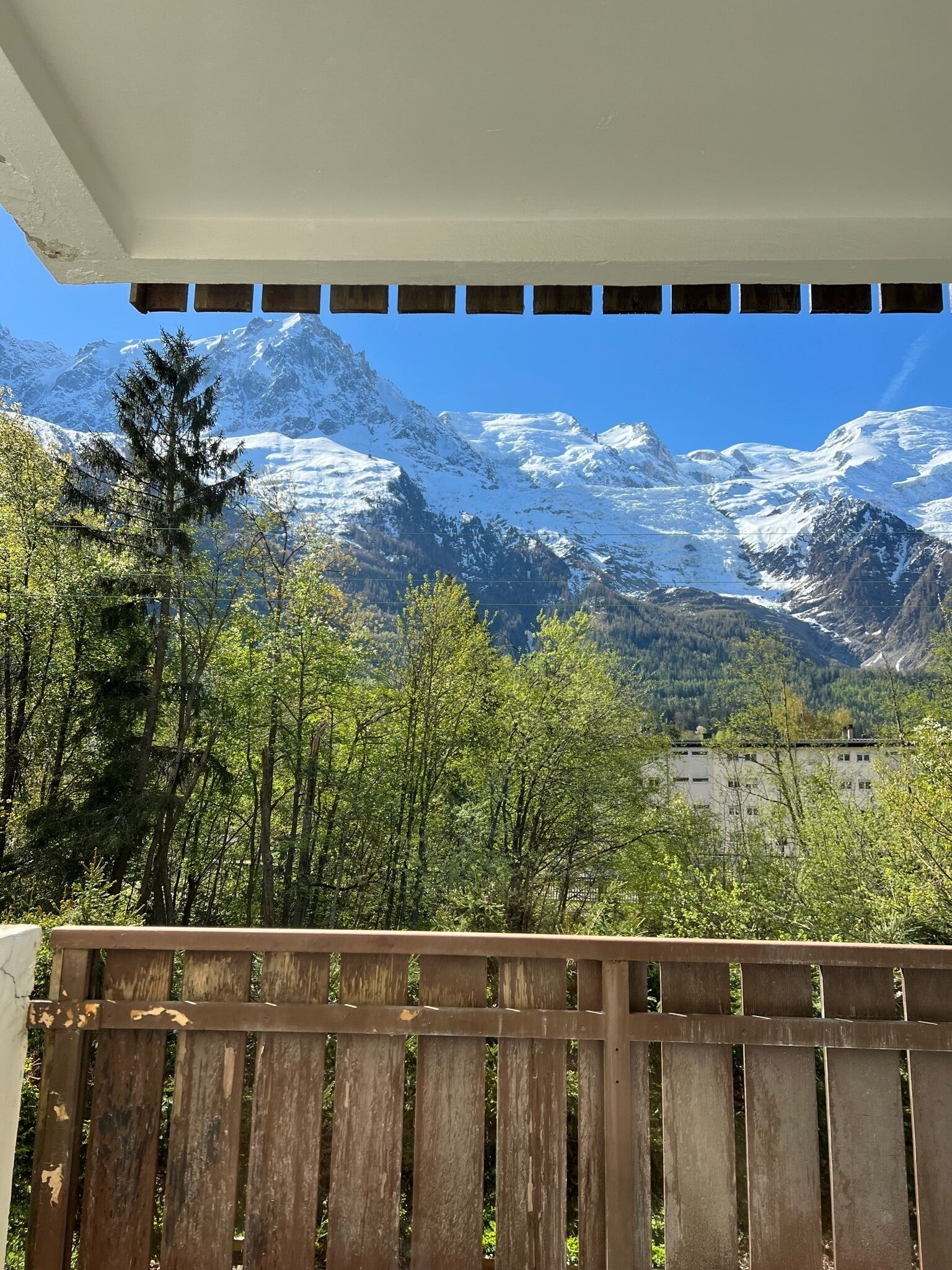 Vista de montanha a partir de uma varanda com guarda-corpo de madeira.