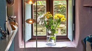Um quarto com uma janela, um vaso com flores e um abajur.