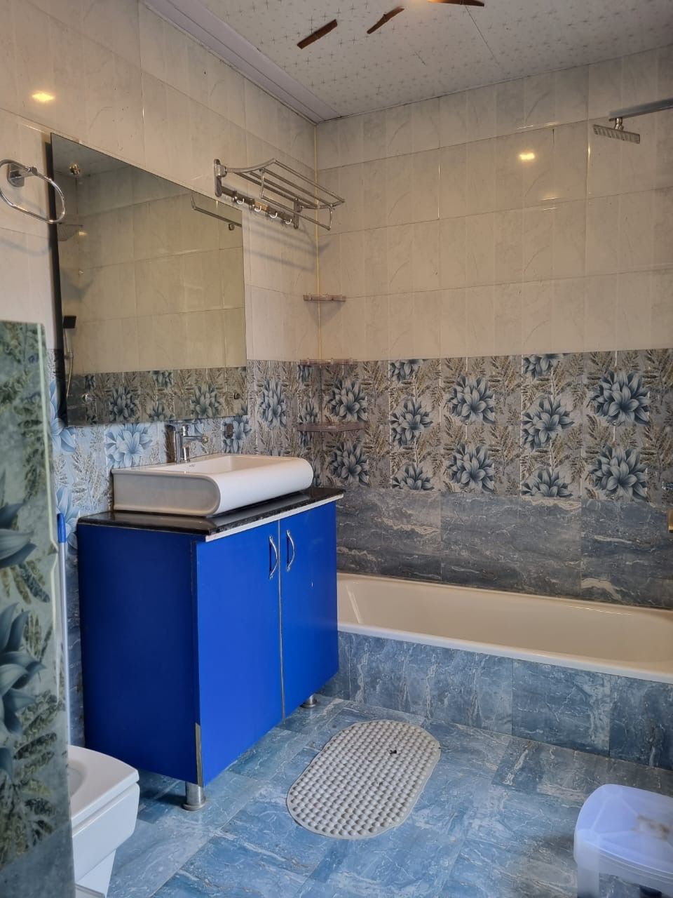 Un baño moderno con bañera, un mueble azul, inodoro y zona de ducha.