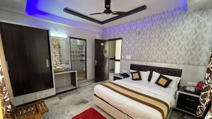 A modern hotel room with a large bed, a desk, a wardrobe, and a bathroom visible through an open door. - Pink Park By Panache Hotel (Bir)