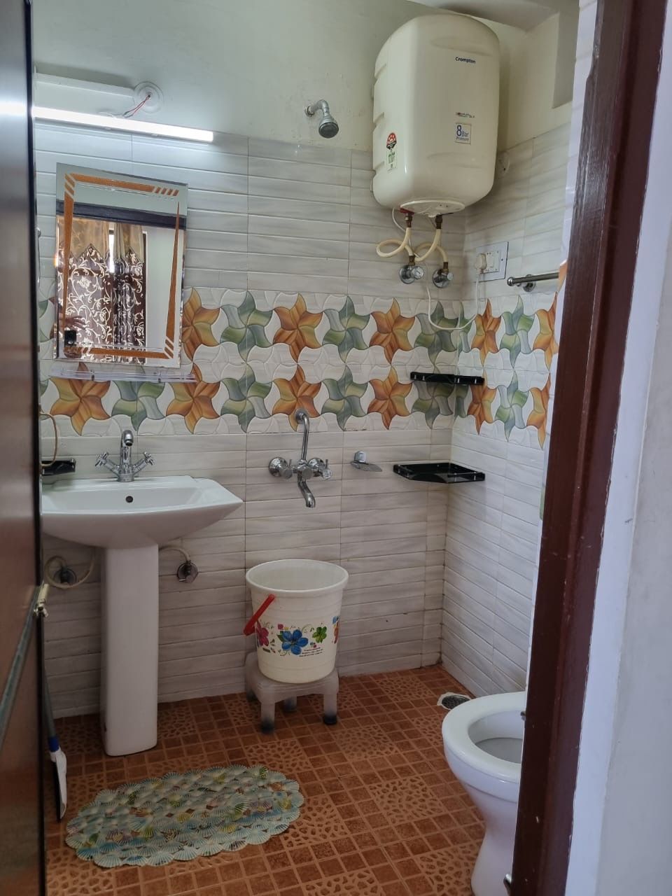 Et badeværelse med vask, toilet og bruser.