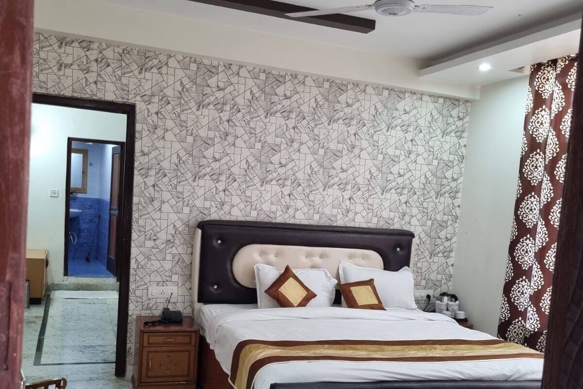 A bedroom with a large bed, a ceiling fan, and a patterned wall.