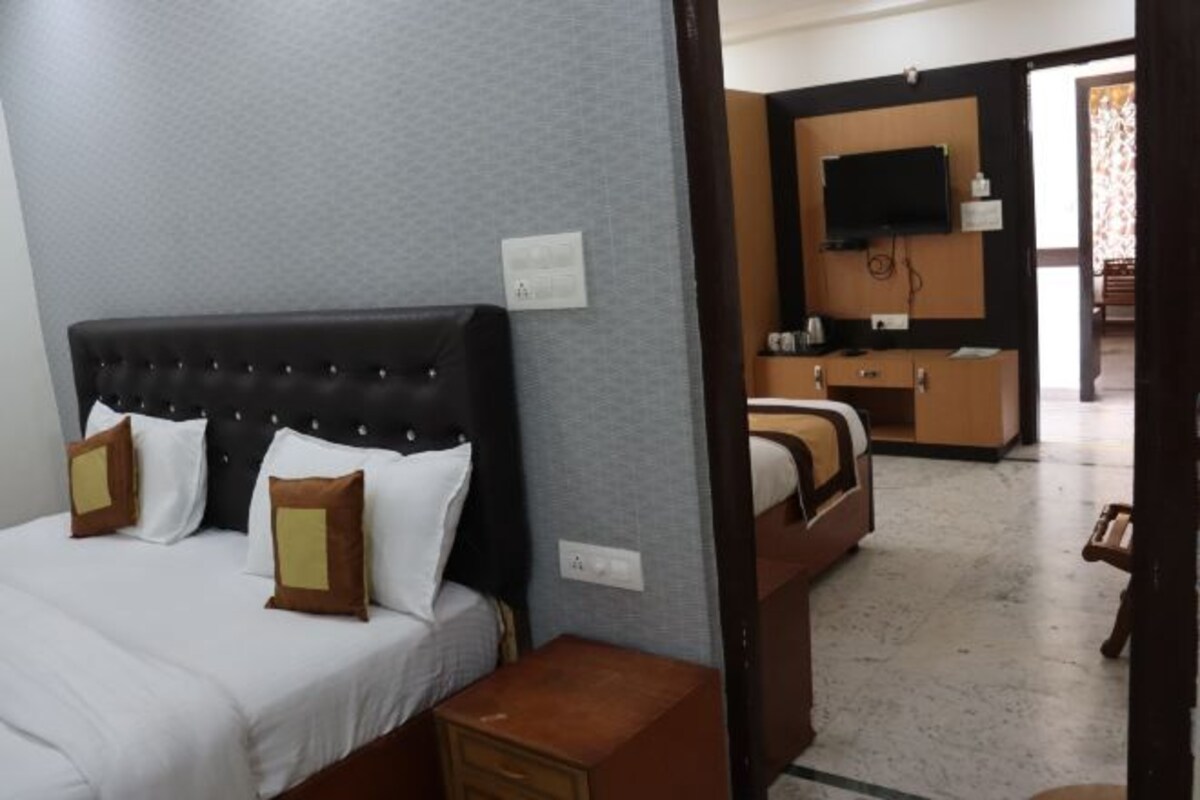 A hotel room with a bed, a bedside table, a dresser, and a television mounted on the wall.