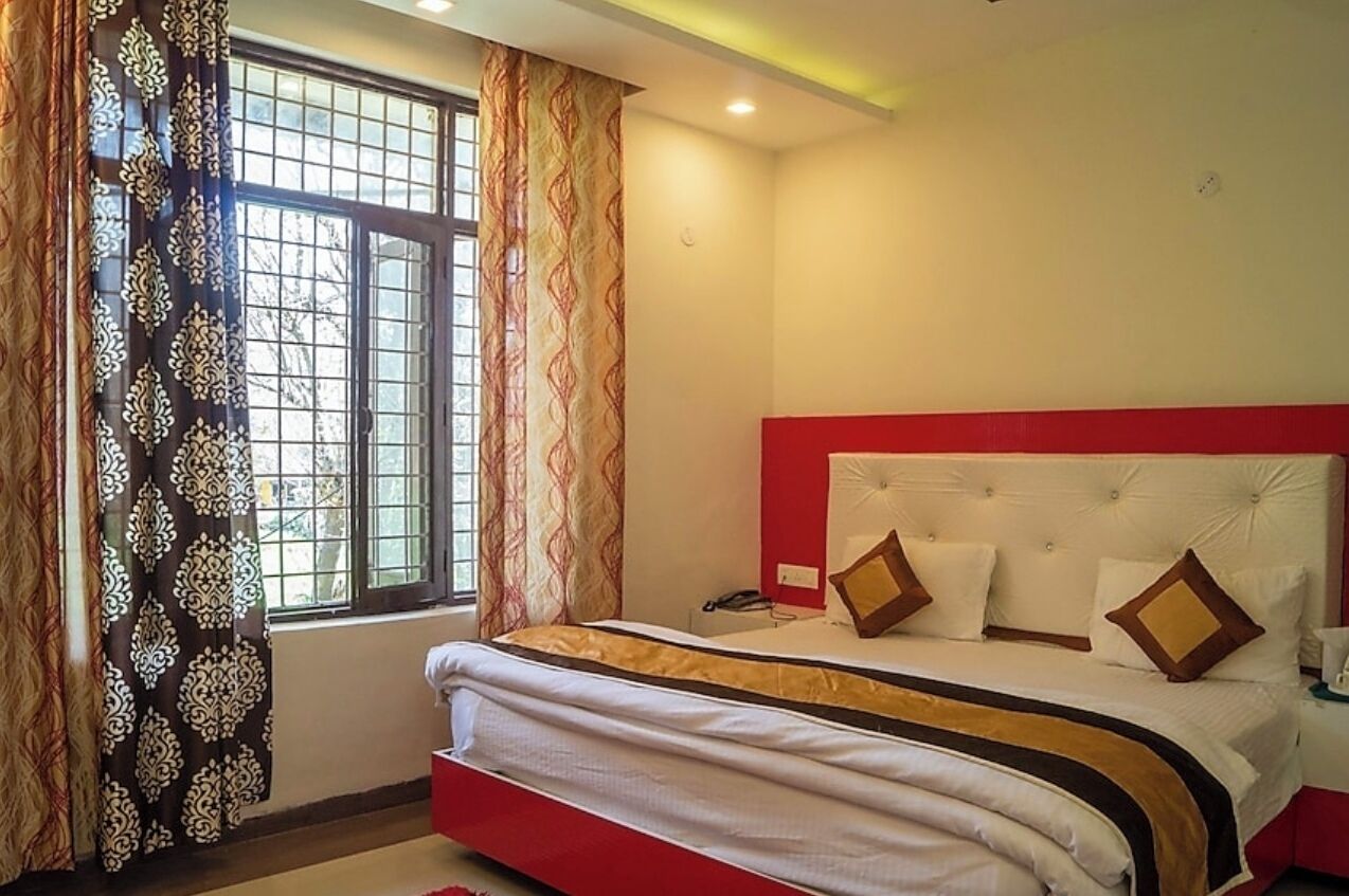 A bedroom with a bed, curtains, and a window.