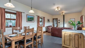 A dining area with a wooden table and chairs, a kitchen with wooden cabinets, and a living area with a sofa.