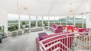 A spacious living area with large windows, a red sofa, and a dining table with red chairs. - Penthouse in York with River Ouse Views (York)