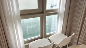 A room with a large window overlooking a body of water, two white chairs, and a wooden door. - THE DECEMBER STAY Busan Ocean Terrace (Busan)
