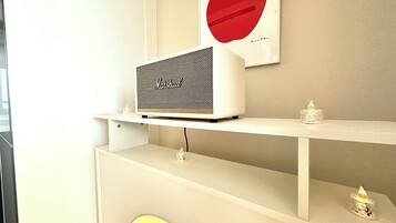 A white Marshall speaker on a shelf with a red apple artwork above it.