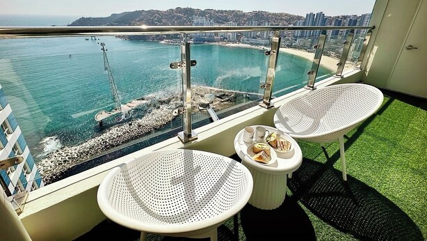 A balcony with two white perforated tables, one with a plate of sandwiches and a cup, and the other with a cup and saucer. - THE DECEMBER STAY Busan Ocean Terrace (Busan)