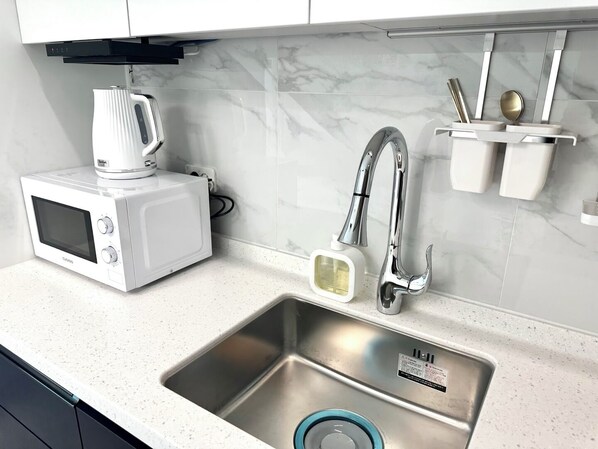 A kitchen with a built-in microwave, stainless steel sink, and a modern faucet.