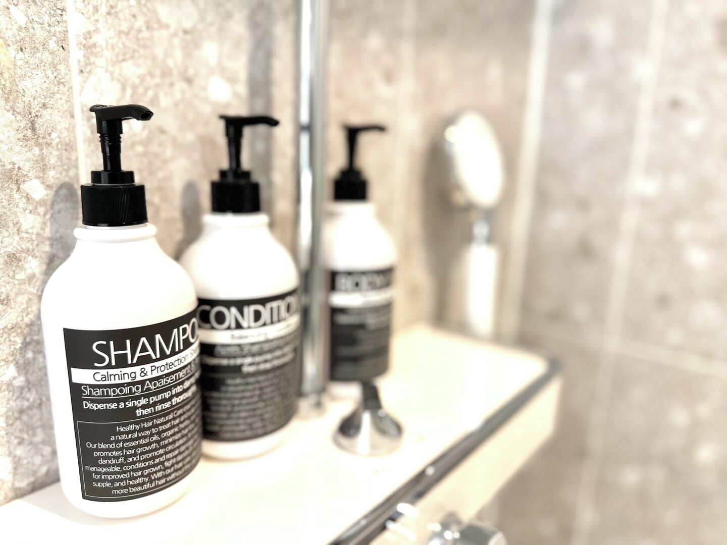 Tres botellas de champú y acondicionador sobre una repisa de baño.