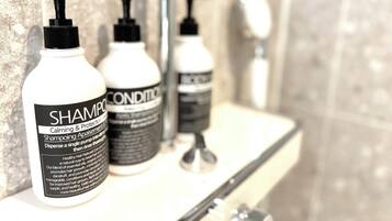 Three bottles of shampoo and conditioner on a bathroom shelf.