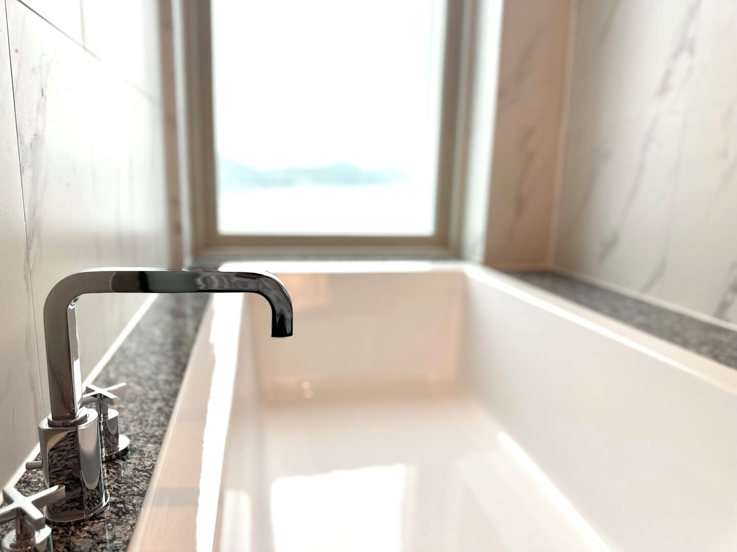 A modern bathroom with a bathtub, a shower, and a window providing a view.