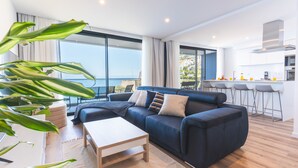 A modern living room with a sofa, a coffee table, and a view of the sea. - Mar Apartment by Atlantic Holiday (Camara de Lobos)