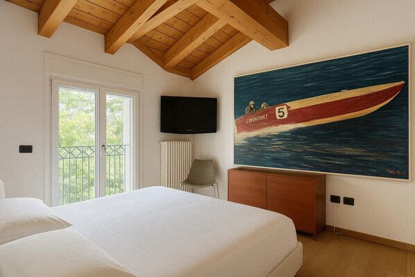 A hotel room with a large bed, a television mounted on the wall, a painting of a boat, and a balcony with a view of trees. - Ca Del Senior - Pool & Lake View (Azzano)