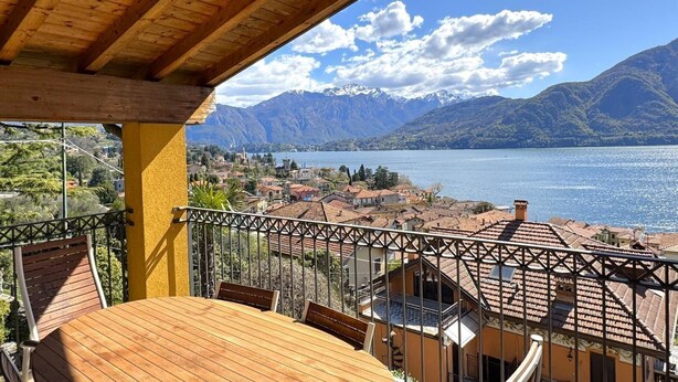 A balcony with a wooden table and chairs overlooking a lake with mountains in the background. - Ca Del Senior - Pool & Lake View (Azzano)