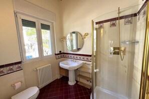 A bathroom with a white sink, a toilet, a shower, and a window with a view of greenery outside. - Ca Del Senior - Pool & Lake View (Azzano)