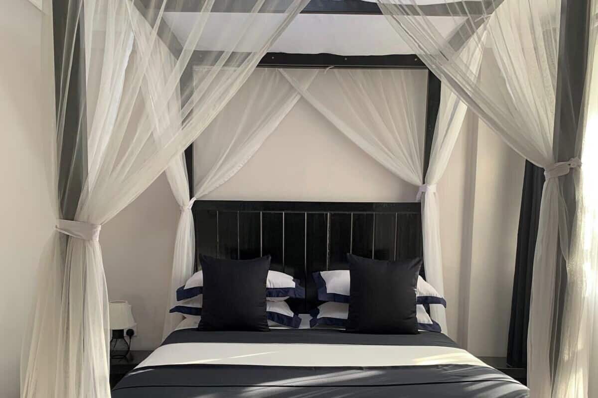 A bed with a black headboard, white bedding, and black pillows.