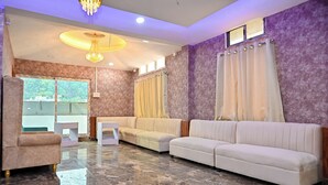 A modern living room with a marble floor, two sofas, a coffee table, and a chandelier. - Holiday Inn Guest House (Guwahati)