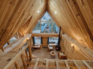 A wooden cabin with a sloped roof, a fireplace, and a view of a mountain landscape. - Shepherd's Lore Camps & Resort (Sangla)