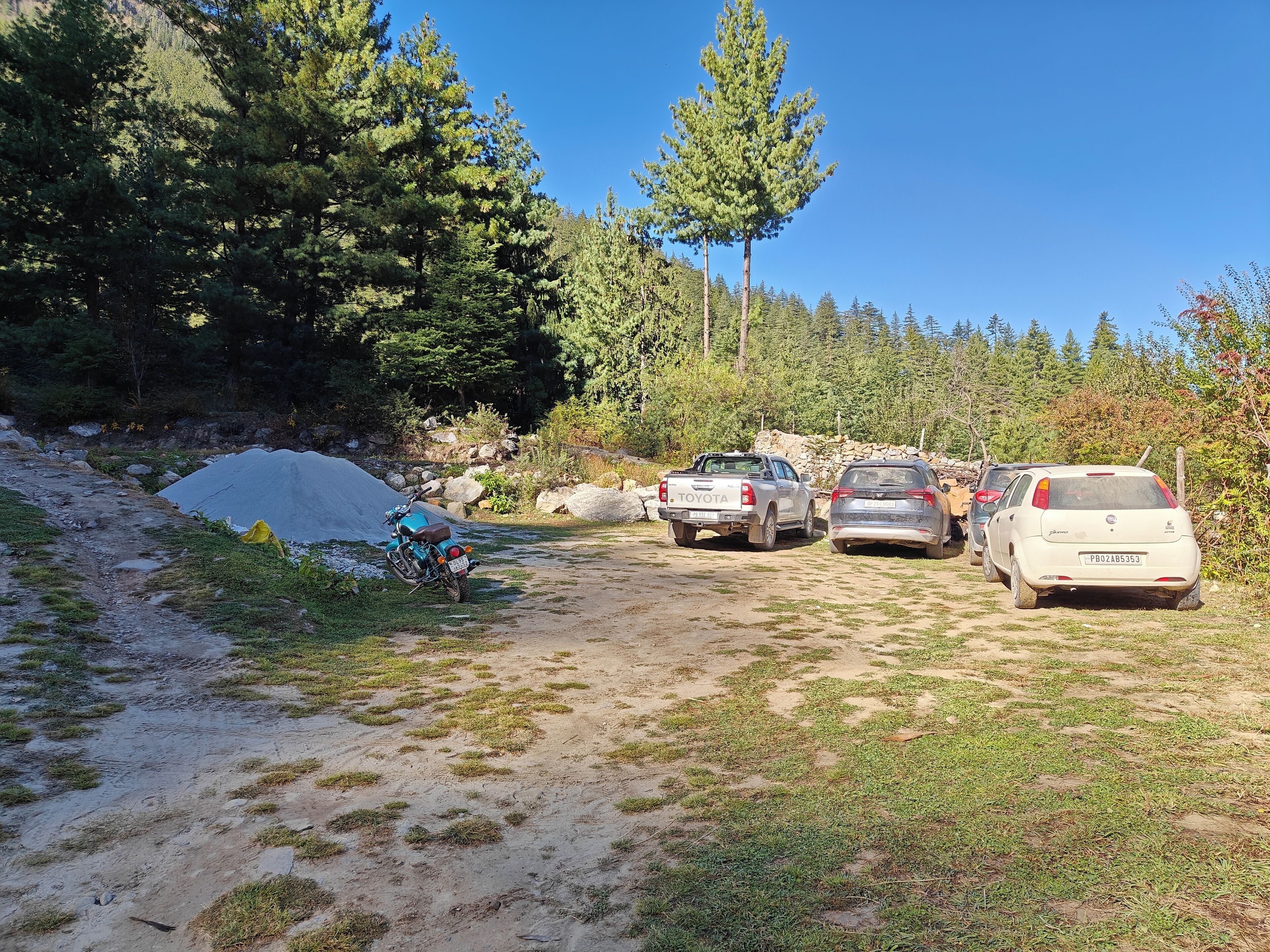 A dirt path with parked vehicles and a motorcycle.
