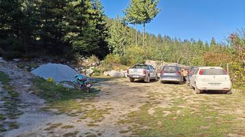 A dirt path with parked vehicles and a motorcycle.