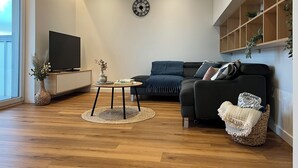 Ein modernes Wohnzimmer mit einer Couch, einem Couchtisch, einem Fernseher und einem Bücherregal.