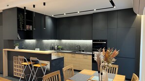 Eine moderne Küche mit dunklen Schränken, einem Holztisch und einer Bar.