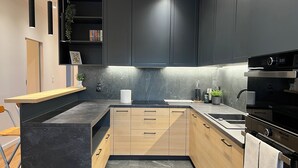 Eine moderne Küche mit dunklen Schränken, einer Holz Arbeitsplatte und einem eingebauten Backofen.