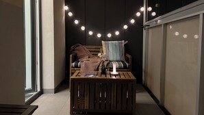 Eine gemütliche Ecke mit einer hölzernen Bank, einem kleinen Tisch mit Büchern und einem Stuhl mit gestreiften Kissen.