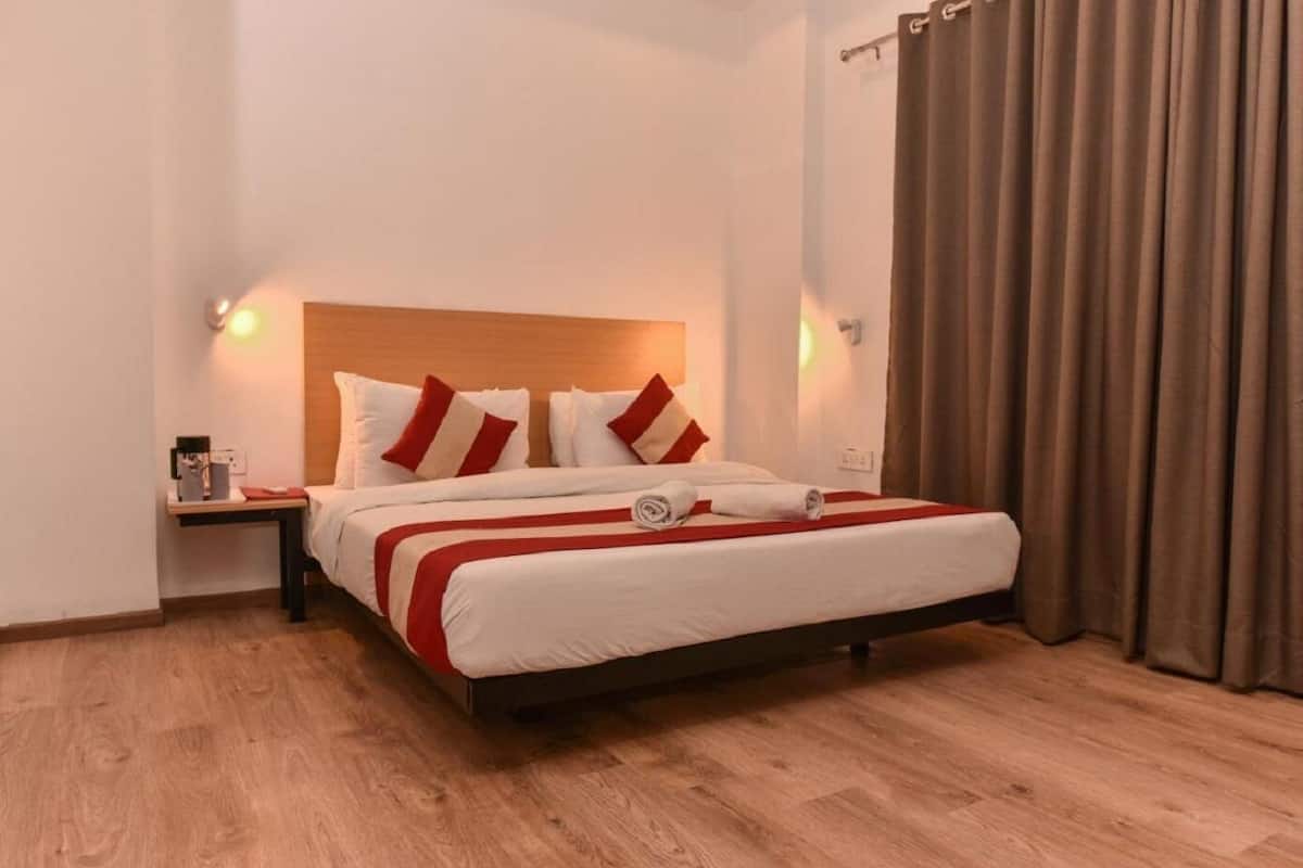 Un lit bien fait, avec une tête de lit en bois, une table de chevet avec une lampe et une fenêtre avec des rideaux.